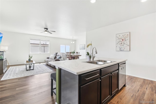 kitchen with wood finished floors, a sink, open floor plan, stainless steel dishwasher, and ceiling fan
