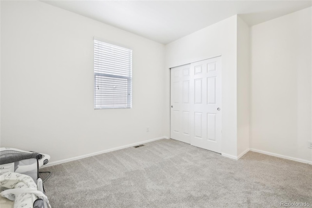 unfurnished bedroom featuring carpet, baseboards, a closet, and visible vents