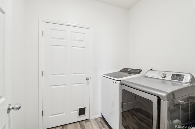 clothes washing area with washing machine and clothes dryer, laundry area, and light wood-style flooring