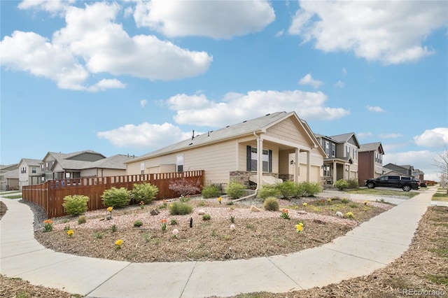 view of home's exterior with fence, a garage, stone siding, and a residential view