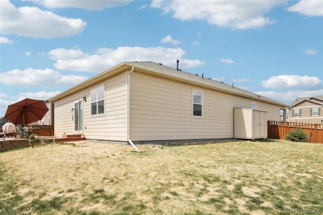 back of property with a yard, fence, a shed, and an outbuilding