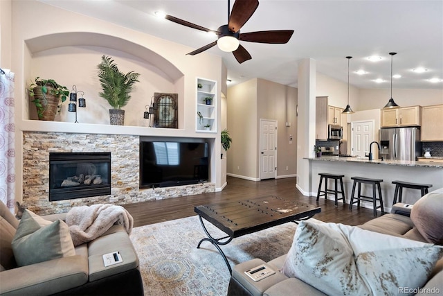 living room with sink, dark wood-type flooring, ceiling fan, a fireplace, and built in shelves