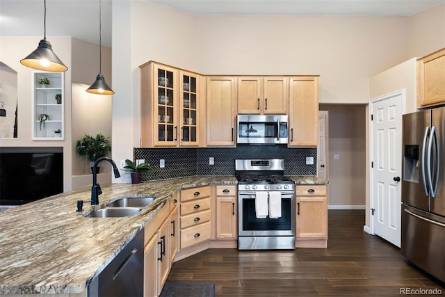 kitchen with appliances with stainless steel finishes, pendant lighting, light brown cabinetry, sink, and light stone counters