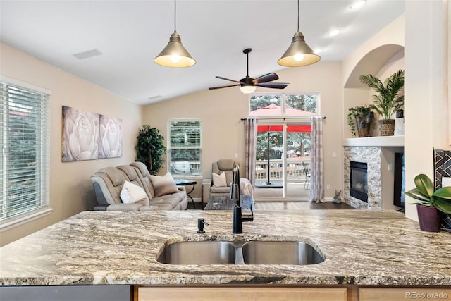 kitchen with light stone countertops, sink, lofted ceiling, and decorative light fixtures