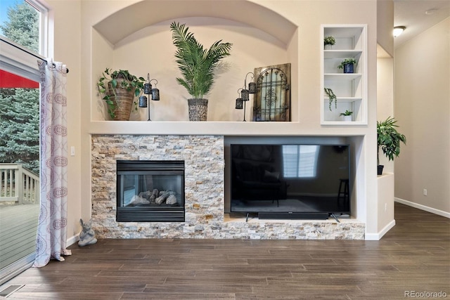 room details with hardwood / wood-style floors, a stone fireplace, and built in features