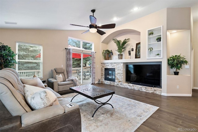 living room featuring ceiling fan, dark hardwood / wood-style floors, a fireplace, built in shelves, and vaulted ceiling