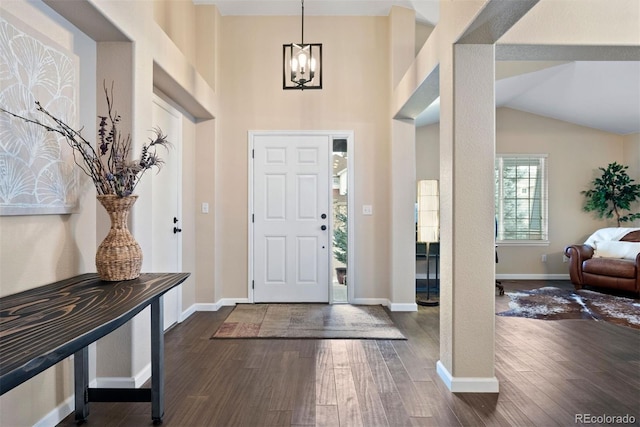 entrance foyer with high vaulted ceiling, dark wood-type flooring, and an inviting chandelier