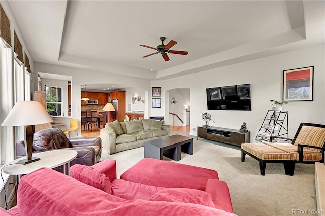 24965 E Roxbury Pl, Aurora, CO 80016 - living room with a tray ceiling, arched walkways, carpet flooring, and a ceiling fan