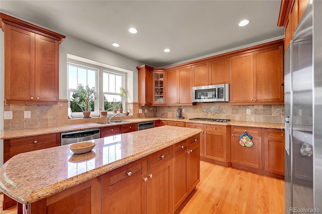 24965 E Roxbury Pl, Aurora, CO 80016 - kitchen featuring stainless steel appliances, recessed lighting, brown cabinetry, light stone counters, and light wood finished floors