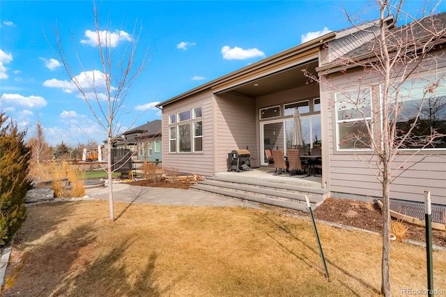 rear view of house with a lawn and a patio