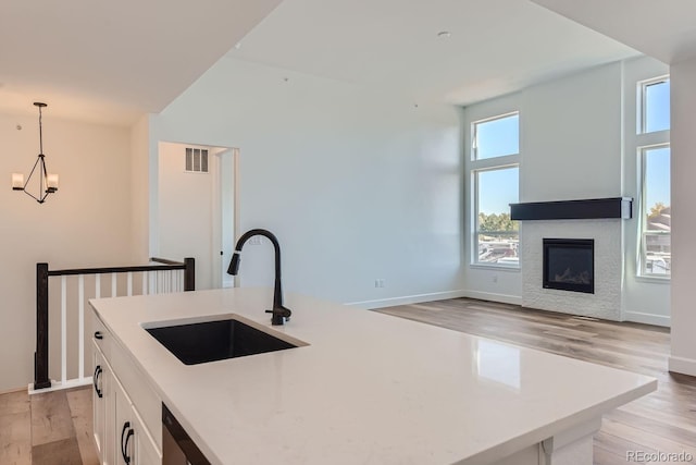 kitchen featuring light hardwood / wood-style floors, white cabinetry, hanging light fixtures, and sink