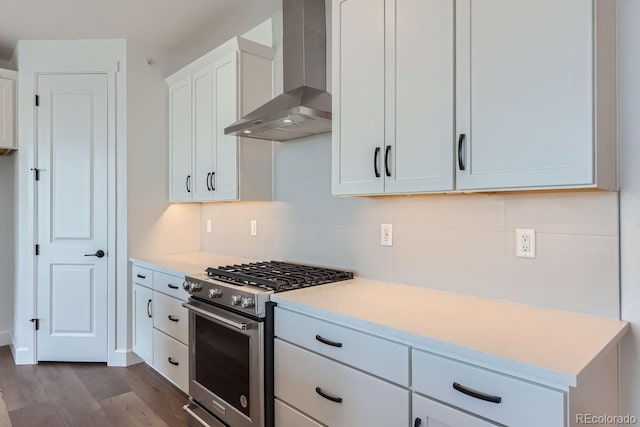 kitchen featuring wall chimney range hood, light hardwood / wood-style flooring, high end stove, backsplash, and white cabinets