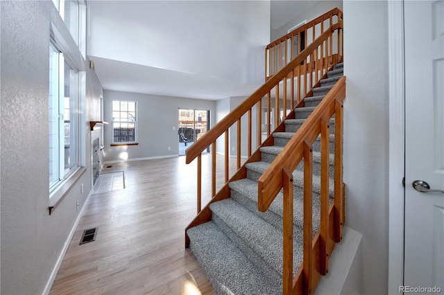 staircase with wood-type flooring and a towering ceiling