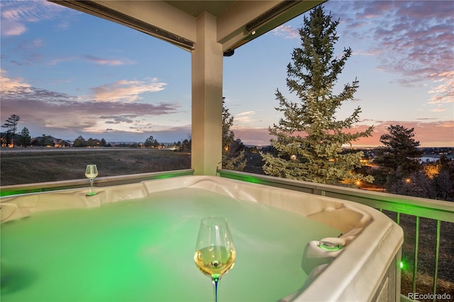 pool at dusk with a hot tub