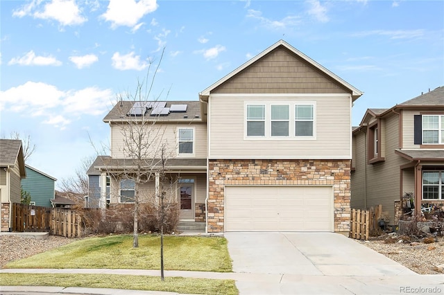 view of front of home featuring driveway, roof mounted solar panels, fence, a front yard, and a garage