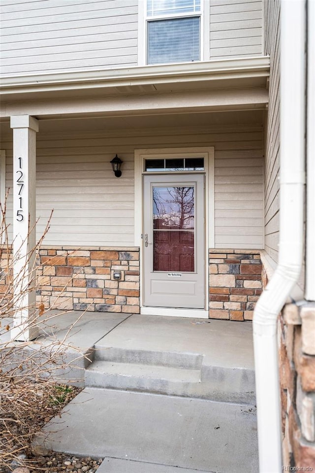 property entrance with covered porch and stone siding