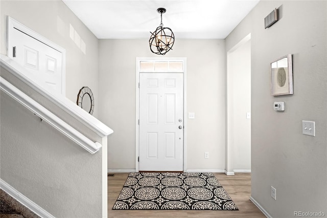 foyer featuring an inviting chandelier, stairway, light wood-style floors, and baseboards