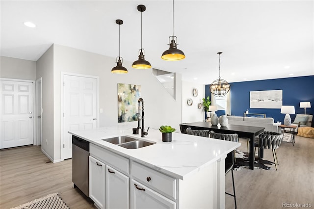 kitchen featuring a center island with sink, a sink, light wood-style floors, white cabinets, and dishwasher