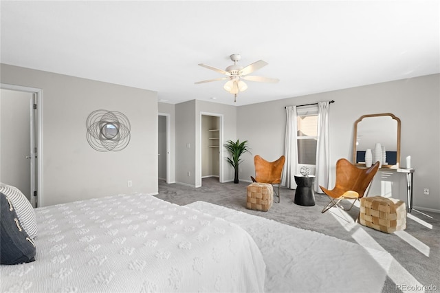 carpeted bedroom featuring a closet, a ceiling fan, a walk in closet, and baseboards