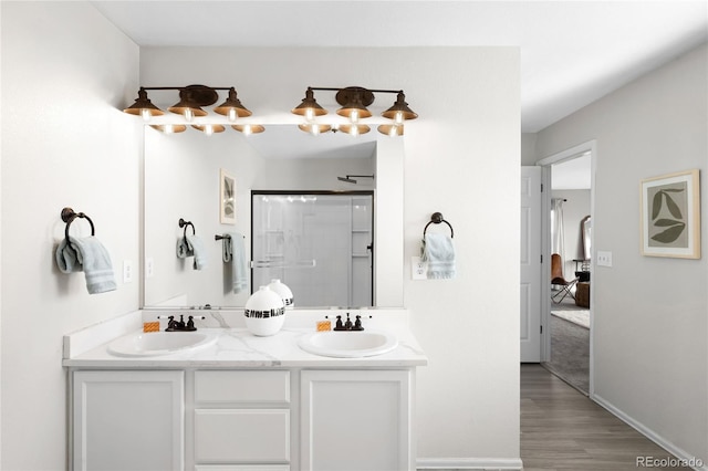 full bathroom featuring double vanity, wood finished floors, walk in shower, and a sink