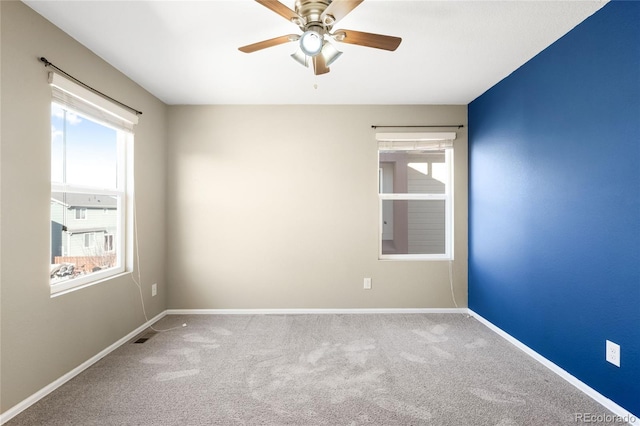 carpeted empty room featuring a ceiling fan and baseboards