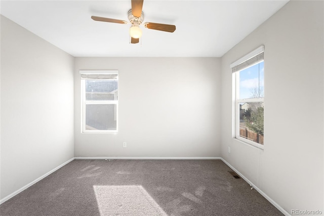 carpeted spare room with visible vents, baseboards, and ceiling fan