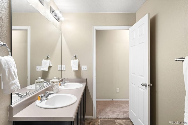 bathroom with double vanity, baseboards, and a sink