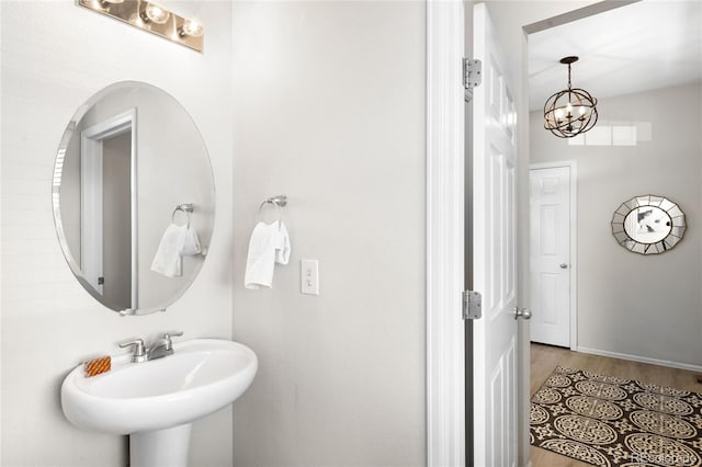 bathroom with wood finished floors, an inviting chandelier, and a sink