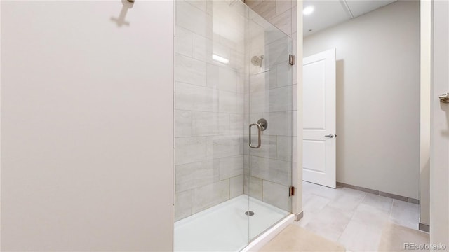 full bathroom with a stall shower, tile patterned floors, and baseboards