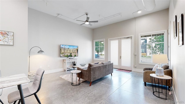 living room with ceiling fan, french doors, concrete floors, and baseboards