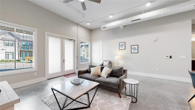 living area with baseboards, a ceiling fan, rail lighting, finished concrete floors, and french doors