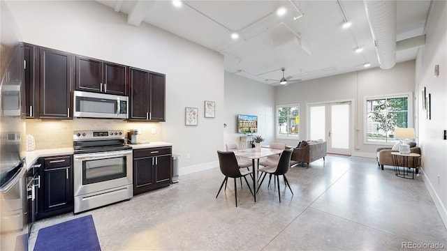 kitchen featuring stainless steel appliances, a high ceiling, concrete floors, and backsplash