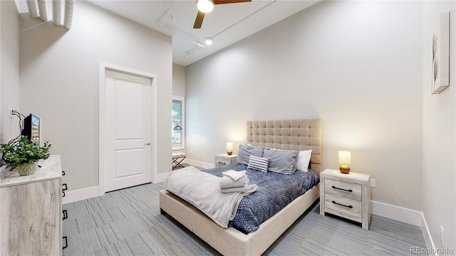 bedroom featuring light wood-type flooring, rail lighting, and baseboards