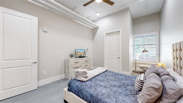 bedroom with light wood-type flooring, ceiling fan, and baseboards