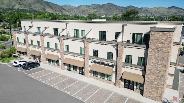 view of building exterior with uncovered parking and a mountain view