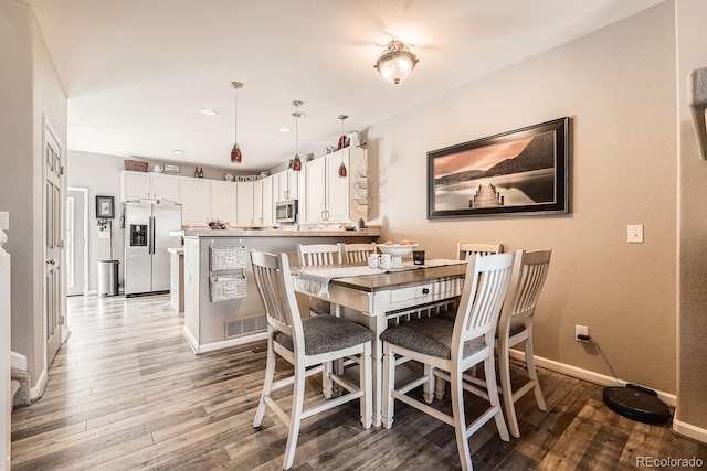 dining area with visible vents, baseboards, and wood finished floors