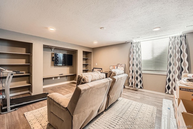 living area featuring built in features, baseboards, a textured ceiling, light wood-style floors, and recessed lighting