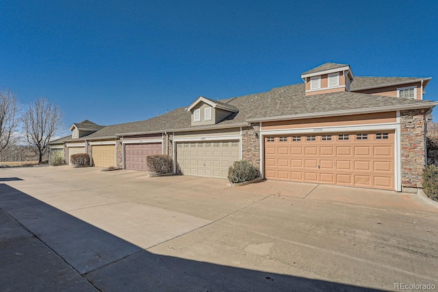 view of front of home with a garage, stone siding, and roof with shingles