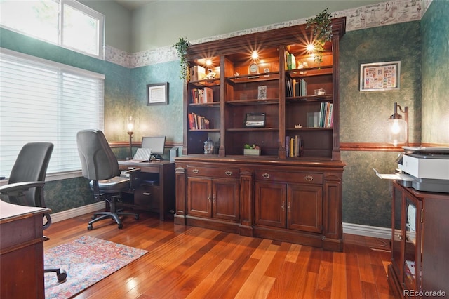 office with wallpapered walls, light wood finished floors, and baseboards