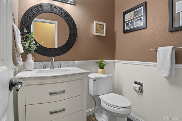 bathroom with toilet, vanity, and baseboards