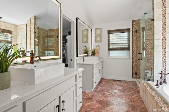 full bath with a shower stall, lofted ceiling, tiled bath, two vanities, and a walk in closet