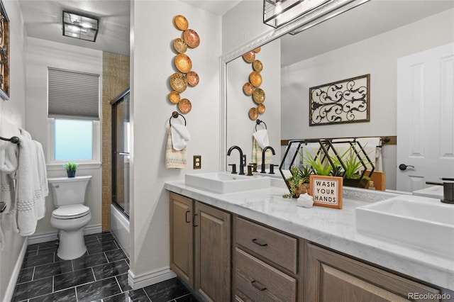 full bath with double vanity, baseboards, toilet, and enclosed tub / shower combo