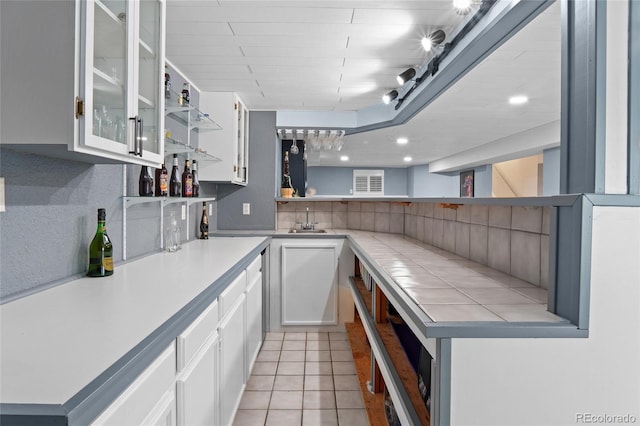 kitchen with open shelves, white cabinetry, a sink, light tile patterned floors, and decorative backsplash