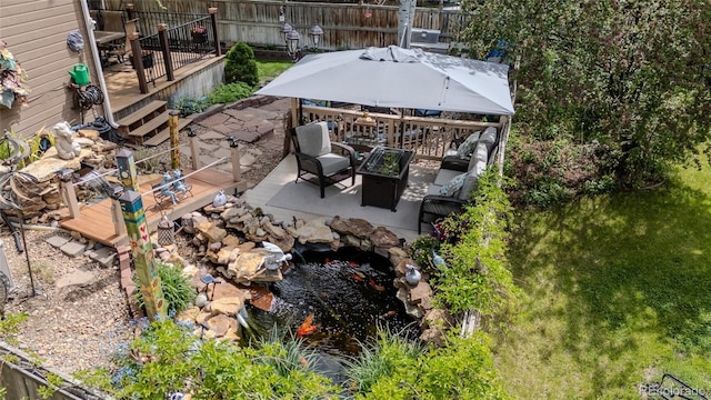 view of yard with a deck, a patio, a small pond, and a fire pit
