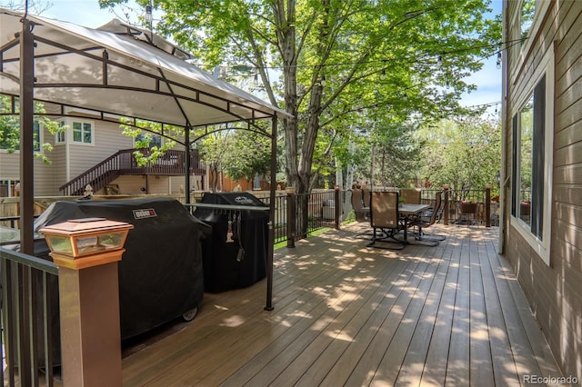 wooden terrace featuring outdoor dining space, a gazebo, and grilling area