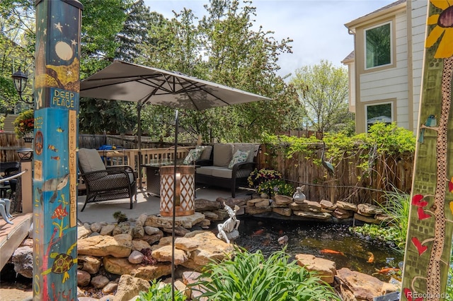 view of patio with a garden pond, an outdoor hangout area, and fence