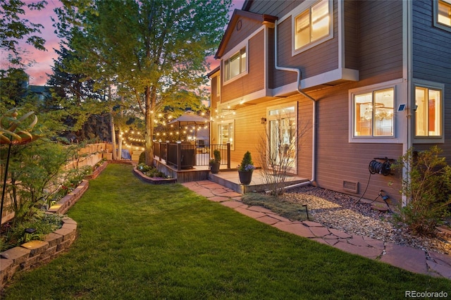 yard at dusk with a yard and a wooden deck