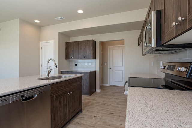 814 N Bently St, Watkins, CO 80137 - kitchen with appliances with stainless steel finishes, a sink, light wood finished floors, tasteful backsplash, and dark brown cabinetry