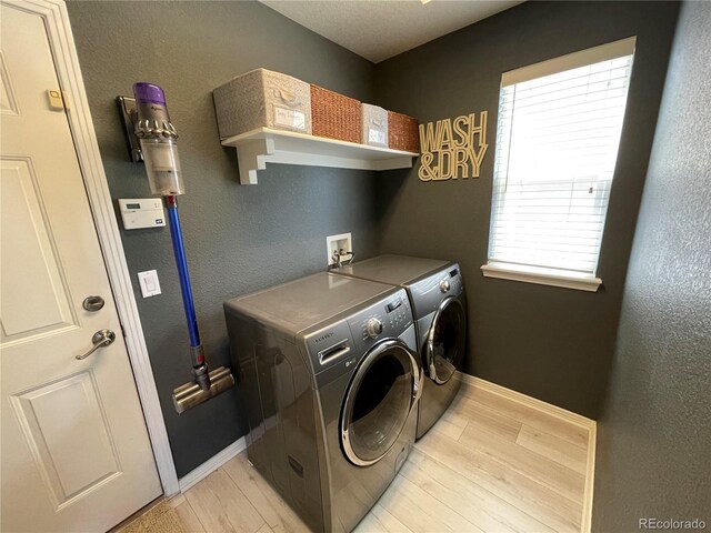 laundry room with washing machine and dryer, light wood-style floors, and baseboards