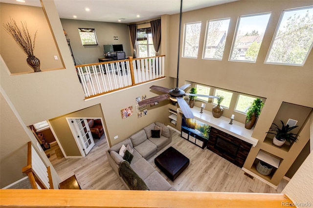 living room featuring wood finished floors, a towering ceiling, recessed lighting, a ceiling fan, and baseboards